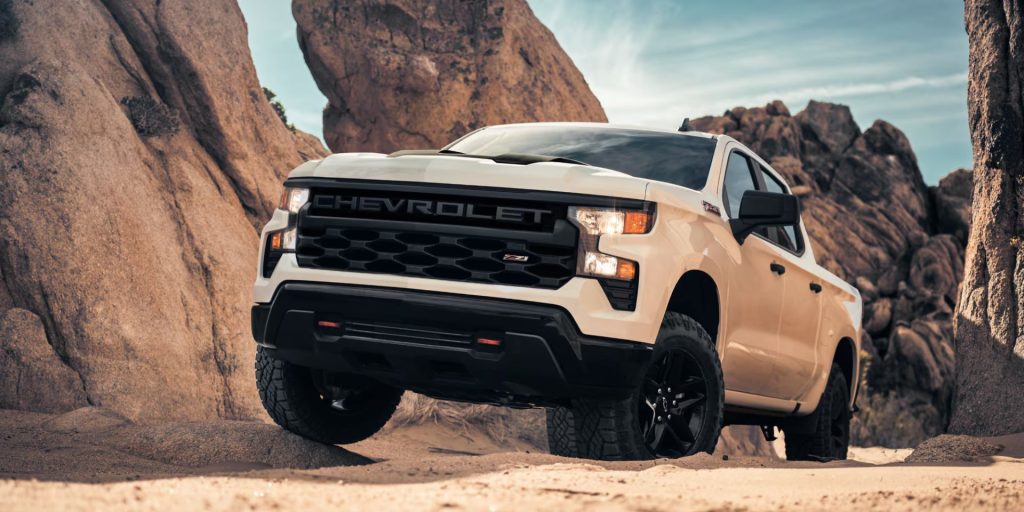 A white Chevrolet Silverado 1500 driving across a rugged desert landscape under clear skies near Princeton Chevrolet GMC in Princeton, IL.